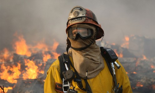 a firefighter looks on as most of the homes in the oakridge mobile home park burn