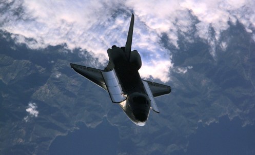 Space Shuttle Atlantis backdropped over a mountainous coastline was photographed on February 16th, 2001 by the three-man Expedition