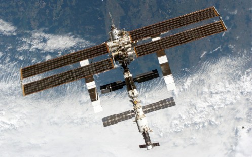 The ISS is backdropped against a cloud-covered part of Earth as the orbital outpost moves away from the Space Shuttle Discovery on August 6th, 2005