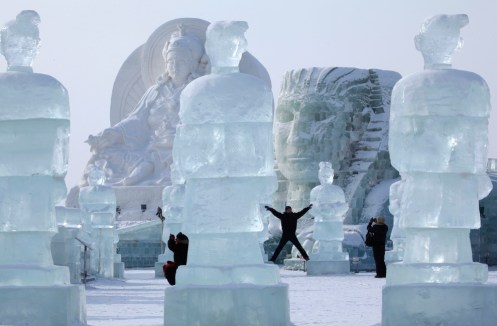 Visitors pose near giant sculptures made from ice and snow before the opening ceremony of the Harbin International Ice and Snow festival in Harbin in northeastern China on Tuesday, Jan. 5, 2010 - Ng Han Guan
