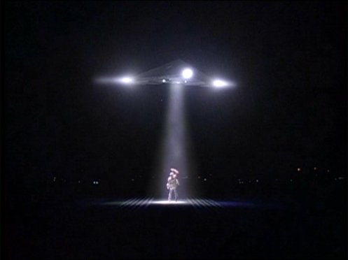 A triangular UFO hovers over Fox Mulder