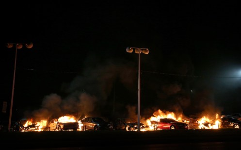 .A row of cars burn at a used car lot during a demonstration.