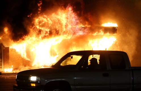 car drives by a burning building during a demonstration on November 25, 2014 in Ferguson, Missouri.