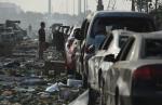 A man looks at a row of damaged cars outside a damaged residential building. (Greg&nbsp;Baker)